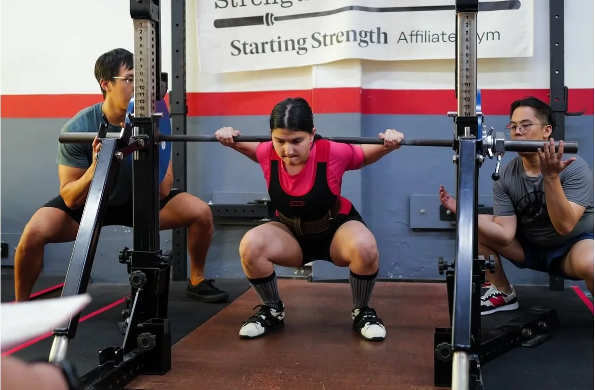 Riya mid-lift on the platform at a powerlifting competition