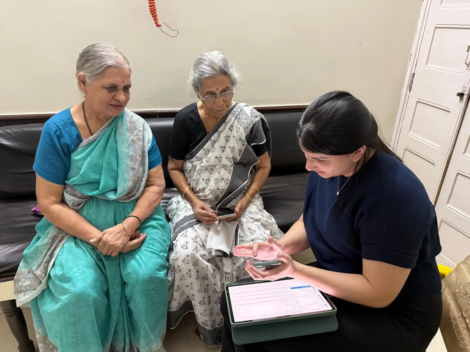 Riya showing two older women how to use a smartphone at a Senior Connect session